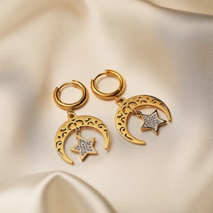 Gold-plated moon and star dangle earrings with zircon on premium silk backdrop