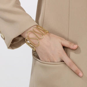 Minimalist gold irregular wave open bangle shown on a model wearing a khaki blazer