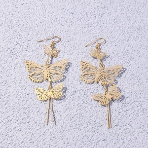 Elegant gold hollow butterfly drop earrings with long metal tassels on purple wall