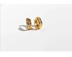 Macro detail of gold-plated hoop earrings with inlaid cubic zirconia on white background