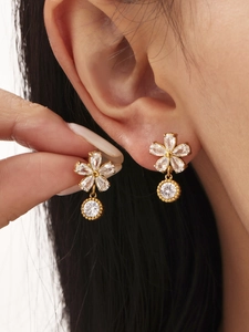 Gros plan de boucles d'oreilles fleur en cristal et métal doré sur modèle