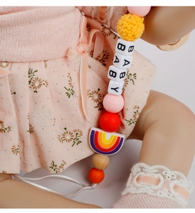 Close-up of rainbow silicone pendant and crochet ball on a beech wood baby pacifier clip