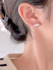 Close-up of a model wearing shell shaped 925 sterling silver stud earrings set