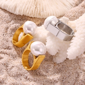 Modern geometric pearl rings in gold and silver finish set on a beach background