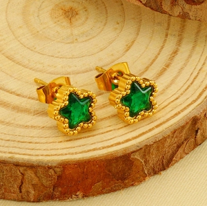 Dettaglio macro degli orecchini a stella placcati oro con zircone verde su legno