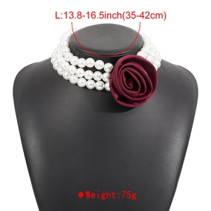 Detailed view of triple-layer pearl choker with large burgundy fabric rose on a bust