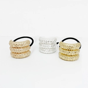 Detail of three elastic hair ties with pleated gold and silver metal textures