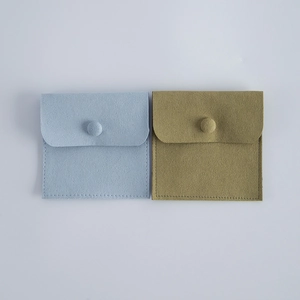 Flat lay of velvet jewelry pouches in light blue and olive green with button closure