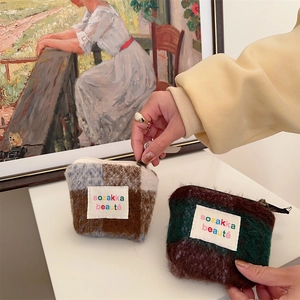 Artistic display of mini plush makeup bags with classic oil painting background