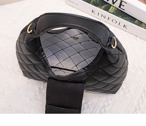 Top view of black quilted handbag interior with textured lining and wide shoulder strap