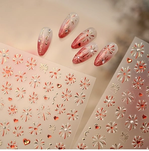 Detailed view of red and gold firework nail stickers with faux pearls and heart motifs