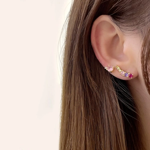 Close-up of model wearing small round earrings with 18k gold plating and multi-color zircons