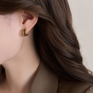 Fashionable C-shaped hoop earrings in gold metal and dark brown enamel on female model