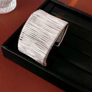 Dettaglio del bracciale rigido in filo metallico argentato multistrato su vassoio nero