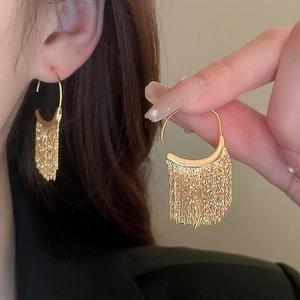 Élégantes boucles d'oreilles créoles dorées avec pampilles portées par un mannequin