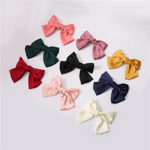 Flat lay of large satin bow hair clips in 9 elegant colors with silk texture and metal clip