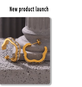Detail of gold-plated wavy hoop earrings featuring square-cut cubic zirconia settings