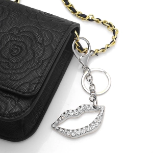 Schwarze Handtasche mit Blumenprägung und Lippen-Schlüsselanhänger mit Strass