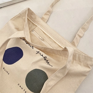 Close-up of the beige canvas tote bag showing the zipper pocket and interior detail