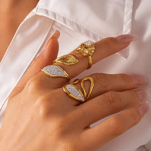 Detail of stacked gold leaf rings with diamonds on model hand with white shirt