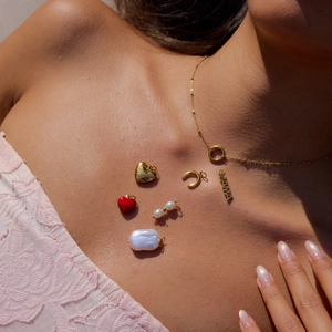 Close-up of gold 18K stainless steel necklace with pearl and MAMA heart charms on model