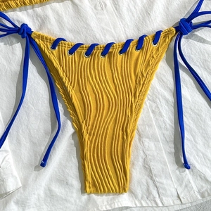 Détail du bas de bikini jaune côtelé avec cordons de serrage bleu marine et œillets en métal