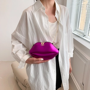 Magenta lip-shaped crossbody bag with gold chain strap shown on a model