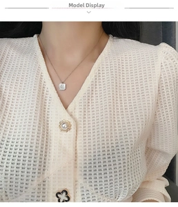 Detailed view of square shell pendant necklace with fine chain on waffled fabric background