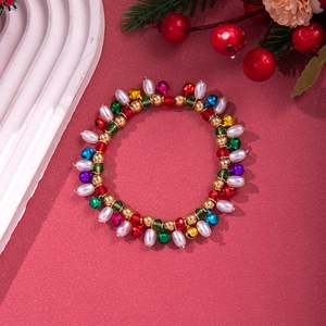 Christmas beaded bracelet with colorful bells and pearls on a festive red background