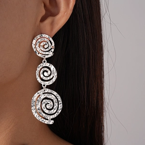 Détail de grandes boucles d'oreilles spirales argentées avec texture martelée
