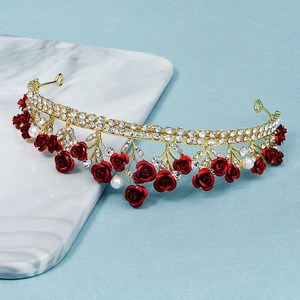 Detailed close-up of a golden bridal crown with red roses, white pearls and sparkling rhinestones