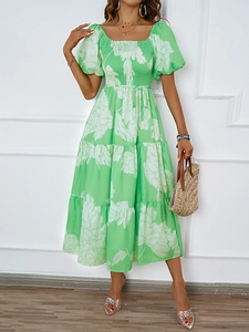 Détail de robe longue fleurie vert et blanc à épaules dénudées avec ourlet à volants