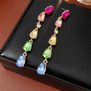 Detailed macro view of colorful teardrop crystal tassel earrings on black texture