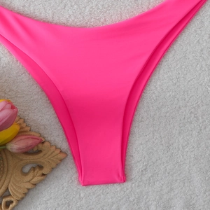 Detail view of hot pink high-cut V-shaped bikini bottoms on white plush background