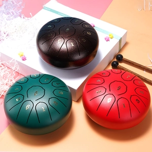 Three steel tongue drums in green, red and brown with mallets and numbers