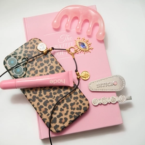 Flat lay of an Evil Eye and Hand of Fatima gold pendant on a pink notebook