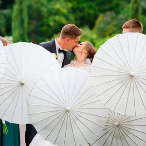 Close-up of white paper wedding umbrellas decorating an outdoor ceremony for a romantic scene
