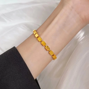 Detailed macro view of gold cuboid links with LOVE engraving on a stainless steel bracelet