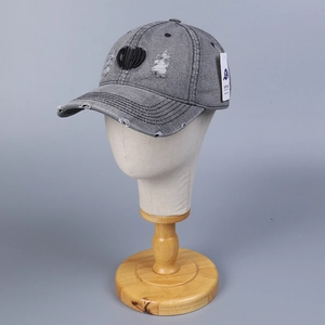 Close-up of gray washed denim baseball cap with heart embroidery and distressed details