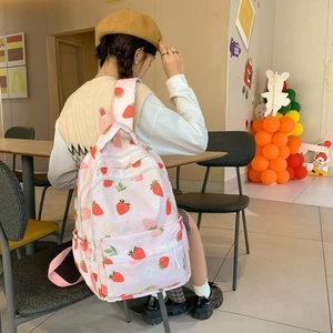Detail view of pink backpack with strawberry prints on model in a casual setting