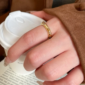 Close-up of gold plated tiger eye ring with irregular textured band on model finger