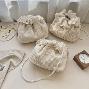 Detailansicht der cremefarbenen Spitzen-Beuteltasche mit elegantem Perlenriemen