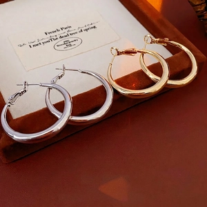 Polished gold and silver hoop earrings with S925 silver needles on jewelry tray
