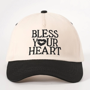 Two-tone beige and black baseball cap featuring BLESS YOUR HEART embroidery with lip icon