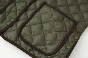 Détail de la veste matelassée vert armée avec bordure en velours côtelé et bouton-pression
