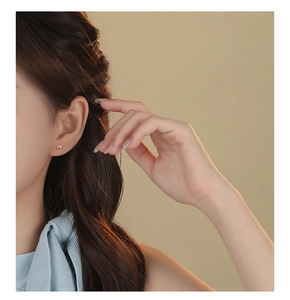 Close-up of a model wearing tiny golden bow earrings made of S999 sterling silver