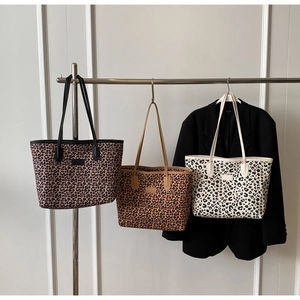 Trois sacs cabas à motif léopard en marron et blanc sur un support métallique