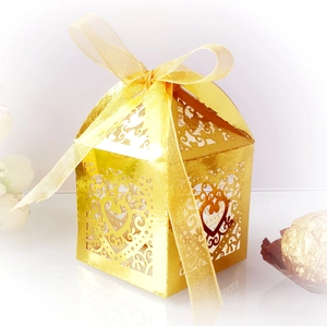 Macro detail of gold laser-cut wedding favor box with heart patterns and silk ribbon bow