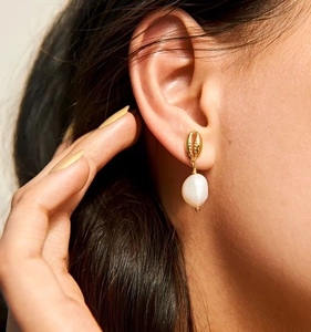 Gros plan de boucles d'oreilles coquillage doré avec perles blanches sur un mannequin