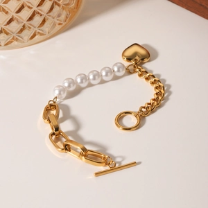 Elegant gold chain pearl bracelet with heart pendant and OT buckle on a clean white surface